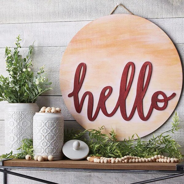 wood hello sign on gray wall with greenery on table